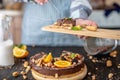 Hand breaks with a fork a piece of chocolate cake with orange and nuts. Concept healthy raw desserts for vegan food Royalty Free Stock Photo
