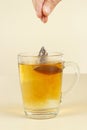 Hand brews tea bag in glass of hot water
