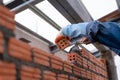 Hand of Bricklayer worker installing brick masonry on exterior wall with trowel putty knife on construction site Royalty Free Stock Photo