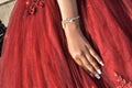 Hand of the bride`s girl with a bracelet on the puffy hem of the red wedding dress Royalty Free Stock Photo