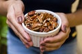 Hand of brunette model holding white pot with pecan nuts