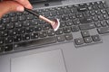 A hand with a brush cleaning a laptop keyboard close up, swiping dust and crumbs from under the buttons Royalty Free Stock Photo