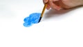 Hand with brush drawing blue cloud with watercolor paints on white paper. Royalty Free Stock Photo