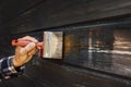 Hand with brush restore paint of old wooden house exterior wall