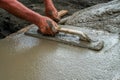 Hand builder with trowel leveling concrete, spreading poured