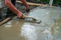 Hand builder with trowel leveling concrete, spreading poured