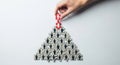 Hand builds pyramid structure with small human figures symbolizing teamwork and hierarchy concept Royalty Free Stock Photo