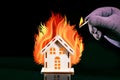 Hand with a burning match sets fire to the house model. Fire safety concept Royalty Free Stock Photo