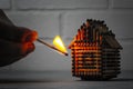 Hand with a burning match sets fire to the house model of matches, risk, property Insurance protection or ignition of combustible Royalty Free Stock Photo