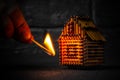 Hand with a burning match sets fire to the house model of matches, risk, property Insurance protection or ignition of combustible Royalty Free Stock Photo