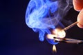 Hand and burning matchsticks with smoke spreading on blue background
