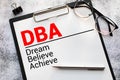 Text Dream Believe Achieve - DBA on white paper