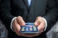 Hand of a business man holding black smartphone with operating s