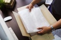 Hand of business man holding Bubble Wrap or Bubble sheet for Wrapping near parcel box on black desk in home office