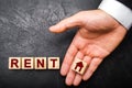 The hand of a businessman in a business suit holds a cube on the palm with a picture of the house to the word rent.