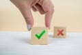 Hand of a businessman chooses checkmark and x sign symbol on cube block