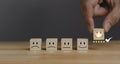 Hand of a businessman chooses a smiley face on wood block cube. best excellent business services rating customer experience Royalty Free Stock Photo