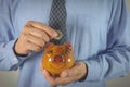 Hand of businessman drop the coin into piggy bank. Financial
