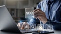Hand of businessman holding a pen pointing to SEO Search Engine Optimization on laptop screen Royalty Free Stock Photo