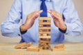 Businessman pulling out or placing wood block on the tower, plan and strategy in business Royalty Free Stock Photo