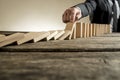 Hand of businessman stopping falling domino pieces