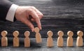 The hand of a businessman takes a wooden figure of a man. Business tactics and strategy, management, business management.