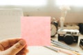 Hand of businesswoman holding post it note with camera and calendar placed background. image for workplace, note, blank concept