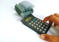 A hand calculating something with calculator with stack of cash money isolated in white background Royalty Free Stock Photo