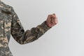 Hand in camouflage shows gesture on gray background. Fingers clenched into a fist. Freeze gesture in the military. Army