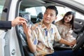 Hand of car sales woman giving the key of the new car to the young attractive owners. Couple purchasing brand new car Royalty Free Stock Photo