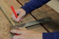 Hand of a carpenter taking measurement on a wooden plank in workshop