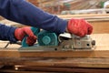 Hand of carpenter using electric planer with wooden plank in carpentry workshop Royalty Free Stock Photo