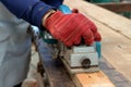 Hand of carpenter using electric planer with wooden plank in carpentry workshop Royalty Free Stock Photo