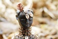 Hand carved wooden doll with shells and feathers