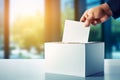 A hand casting a vote in a white ballot box, with a warm sunrise glow in the background