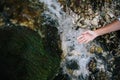 Hand catching water from the springwater. Moss and brook background