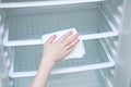 Hand caucasian girl with a white rag washes the fridge.
