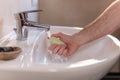 Hand of caucasian man holding antibacterial soap under running water tap. Washing hands, personal hygiene, hand sanitizing Royalty Free Stock Photo