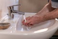 Hand of caucasian man holding antibacterial soap under running water tap. Washing hands, personal hygiene, hand sanitizing Royalty Free Stock Photo