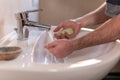 Hand of caucasian man holding soap and testing water temperature under running water tap. Washing hands, personal hygiene Royalty Free Stock Photo