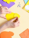 The hand of a caucasian teenage girl glues a decorative eye on a felt yellow chick Royalty Free Stock Photo