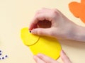 The hand of a caucasian teenage girl glues a decorative eye on a felt yellow chick Royalty Free Stock Photo