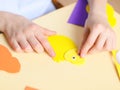 The hand of a caucasian teenage girl sticks a decorative eye on a yellow felt chick while sitting at a table Royalty Free Stock Photo