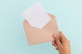 Hand of caucasian woman holding opened envelope with letter over pale blue background Royalty Free Stock Photo