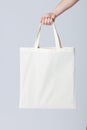 Hand of caucasian woman holding white canvas bag with copy space on grey background Royalty Free Stock Photo