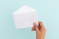 Hand of caucasian woman holding white opened envelope over pale blue background Royalty Free Stock Photo