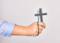Hand of caucasian young catholic woman holding christian cross over isolated white background Royalty Free Stock Photo