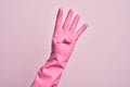 Hand of caucasian young man with cleaning glove over isolated pink background counting number 4 showing four fingers Royalty Free Stock Photo