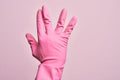 Hand of caucasian young man with cleaning glove over isolated pink background greeting doing Vulcan salute, showing back of the