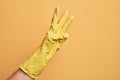 Hand of caucasian young man with cleaning glove over isolated yellow background counting number 3 showing three fingers Royalty Free Stock Photo